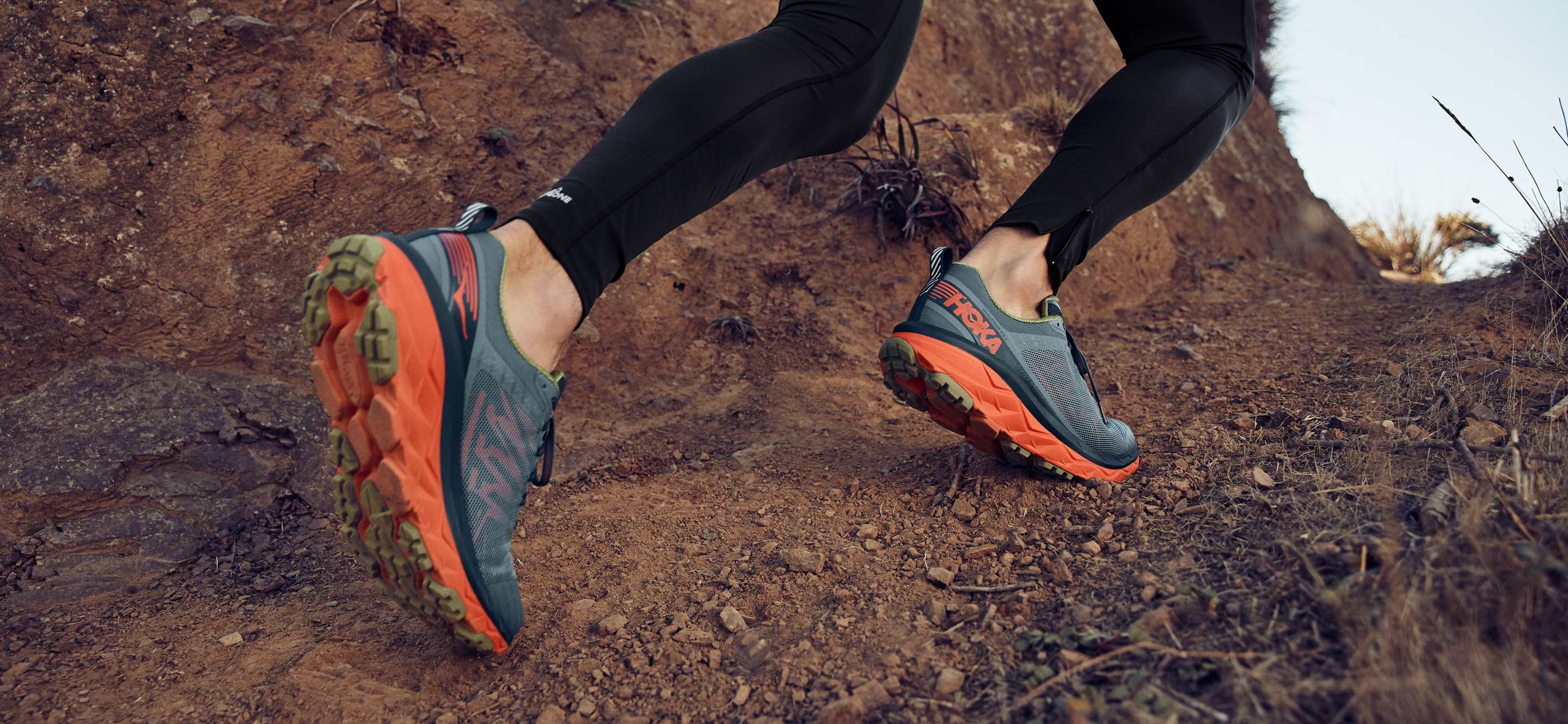 Runners wearing Hoka One One running shoes on a dirt trail.
