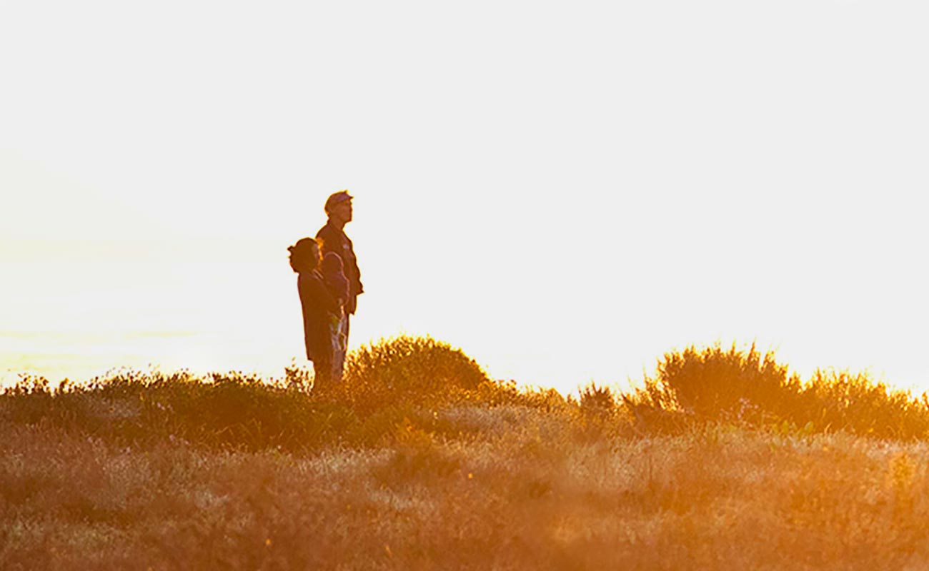 Hiker standing on ridge looking at sunset.