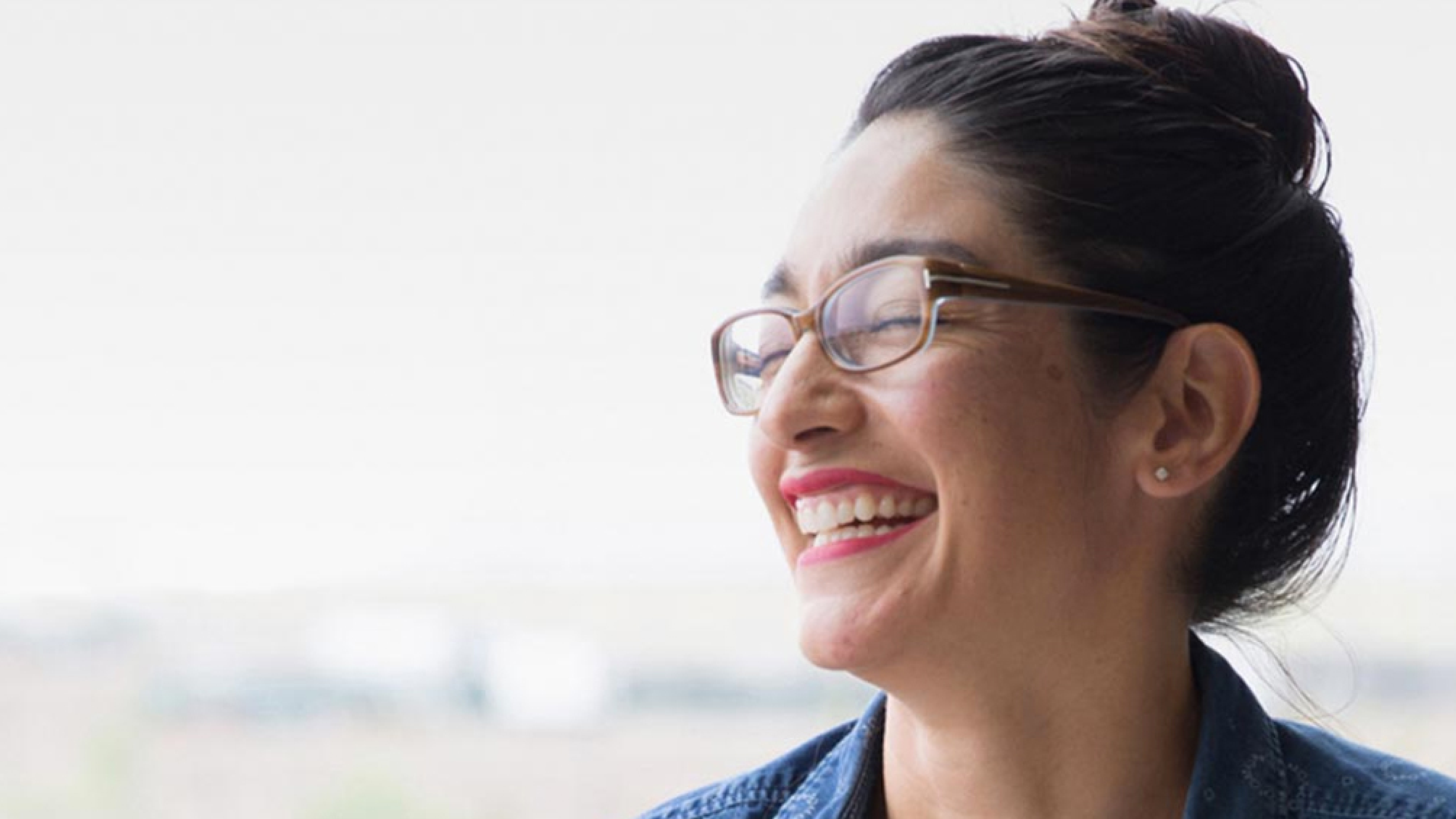 Headshot of woman wearing glasses laughing.