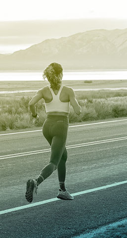 woman running on road in front of mountains